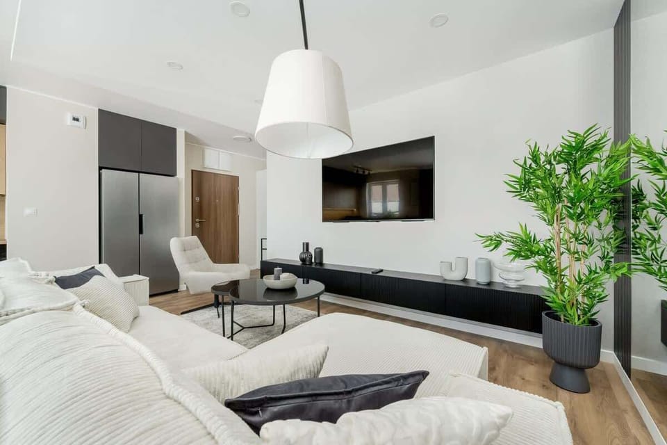 Another view of the living room reveals a bright space filled with greenery and soft fabrics – perfect for rest and conversation.