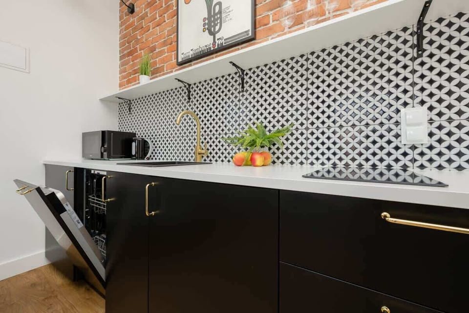 Kitchen details like a gold faucet, black cabinets and geometric tiles create a modern, well-designed cooking space.