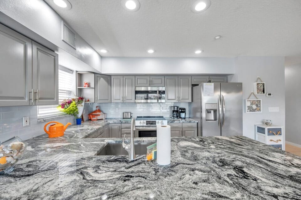 Sleek kitchen island w/ granite counters, bar seating & bright, modern finishes.