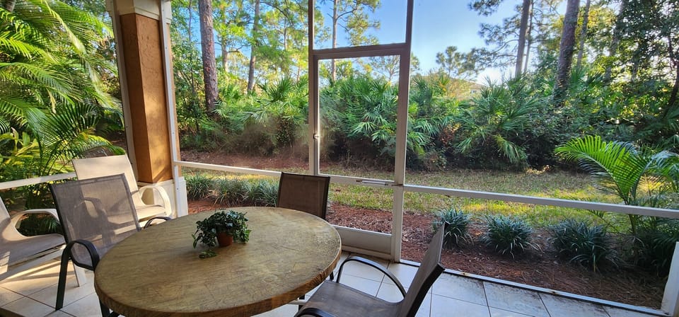 Private screened patio with outdoor seating and peaceful views of the surrounding landscaping.