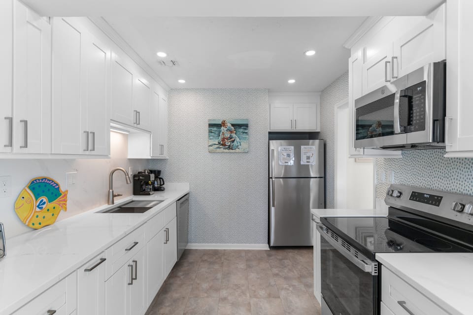 Your bright, modern kitchen features pristine white cabinets, stainless appliances, and playful coastal artwork to inspire culinary adventures.