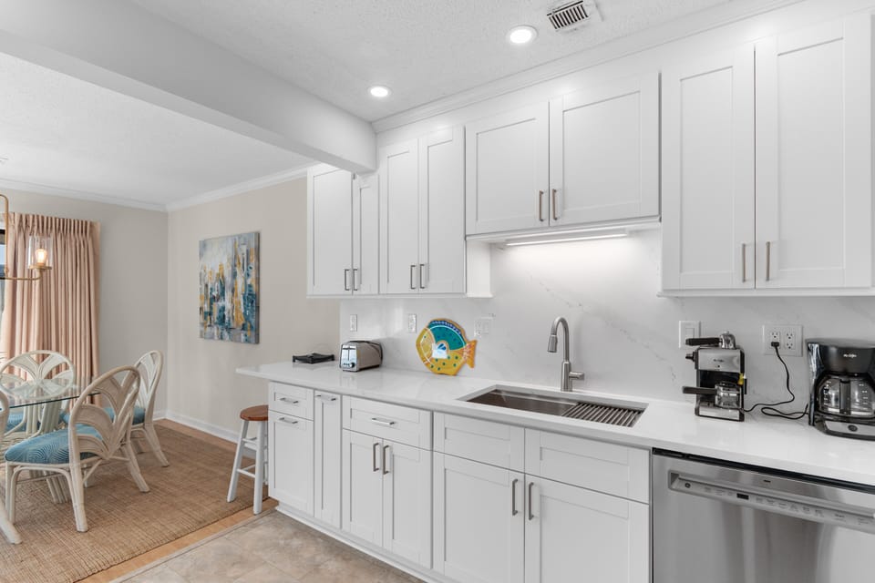 Your fully equipped kitchen features pristine white cabinets, quartz counters, and modern appliances for preparing meals during your stay.