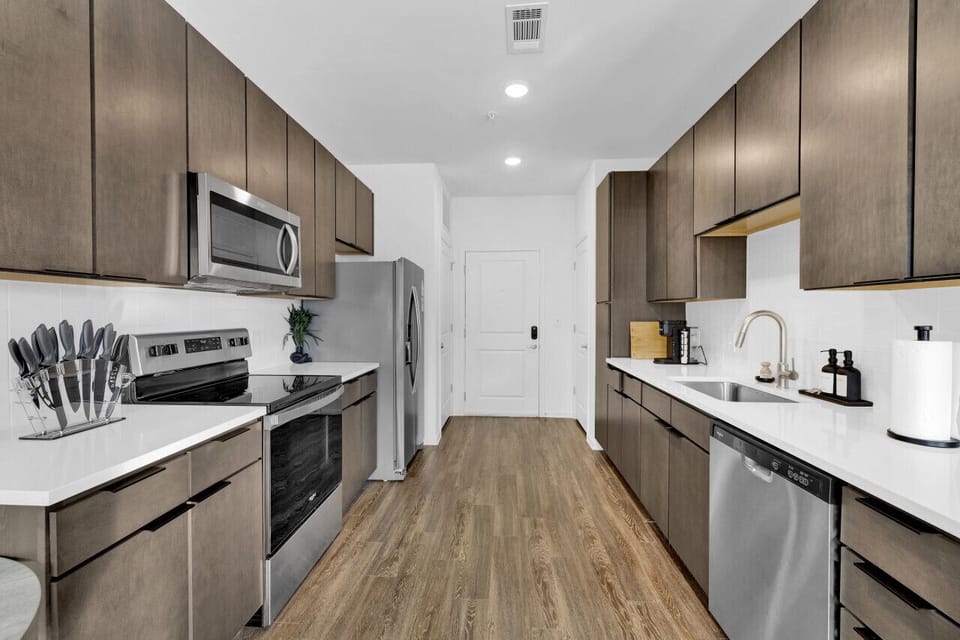 Modern kitchen with sleek stainless steel appliances and neatly arranged utensils, perfect for effortless cooking during your short-term rental stay.
