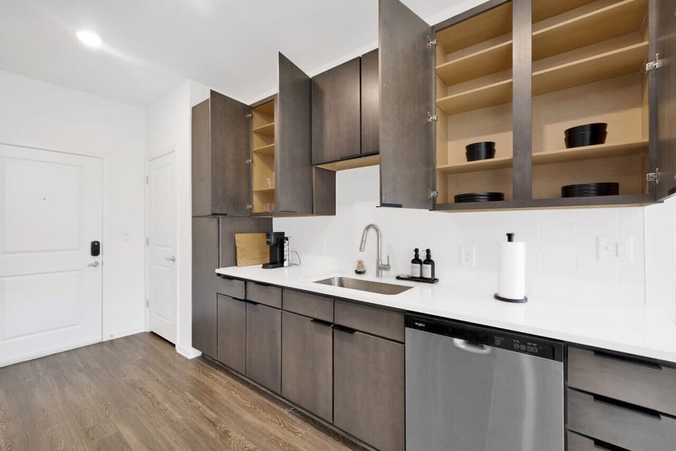 Modern kitchen with sleek stainless steel appliances and neatly arranged utensils, perfect for effortless cooking during your short-term rental stay.
