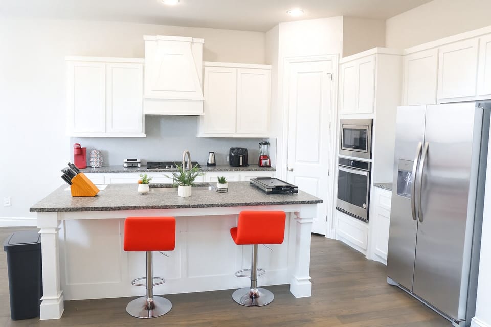 Clean, modern kitchen with pops of red and greenery
