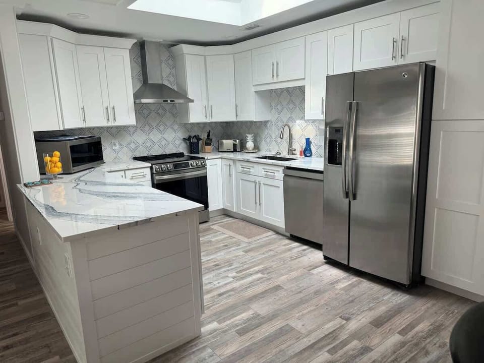 A contemporary kitchen with crisp white cabinetry and high-end stainless steel appliances.