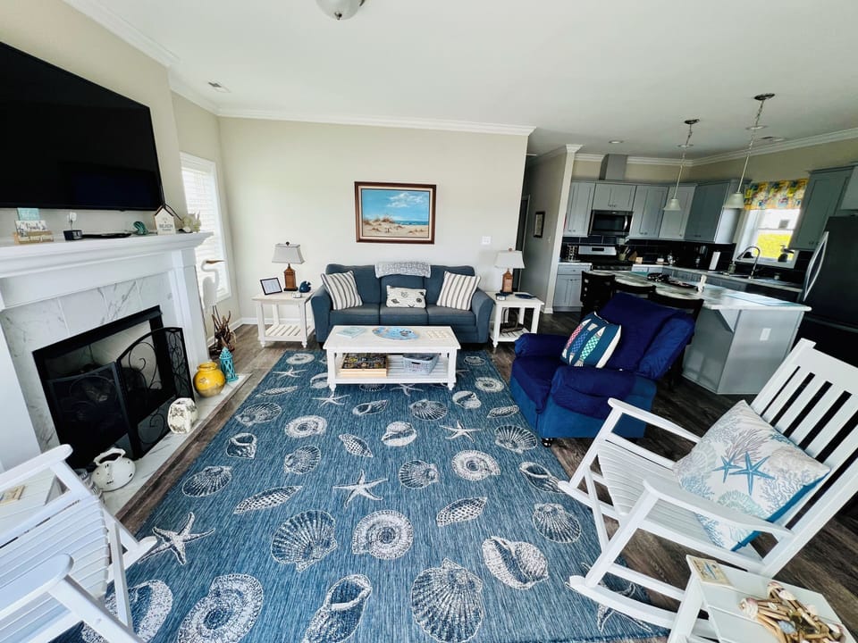 Bright and inviting open-concept living area with comfortable seating, coastal décor, and large windows showcasing beautiful waterway views.