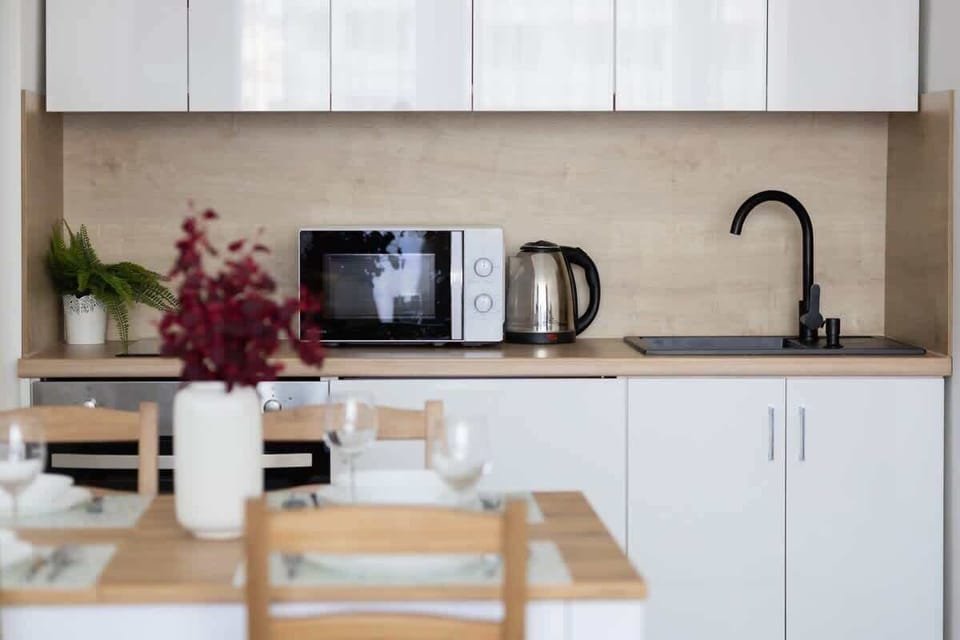 Modern kitchenette with white furniture and high-quality appliances.