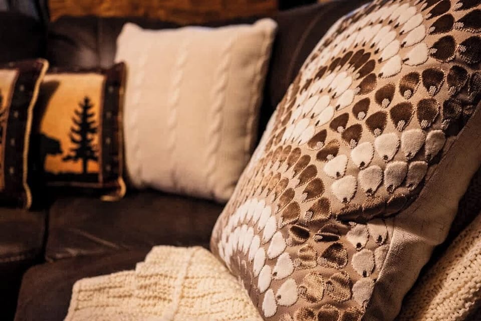 Warm earth tones, cabin-themed pillows, and soft knit throws invite you to unwind in true Smoky Mountain style.