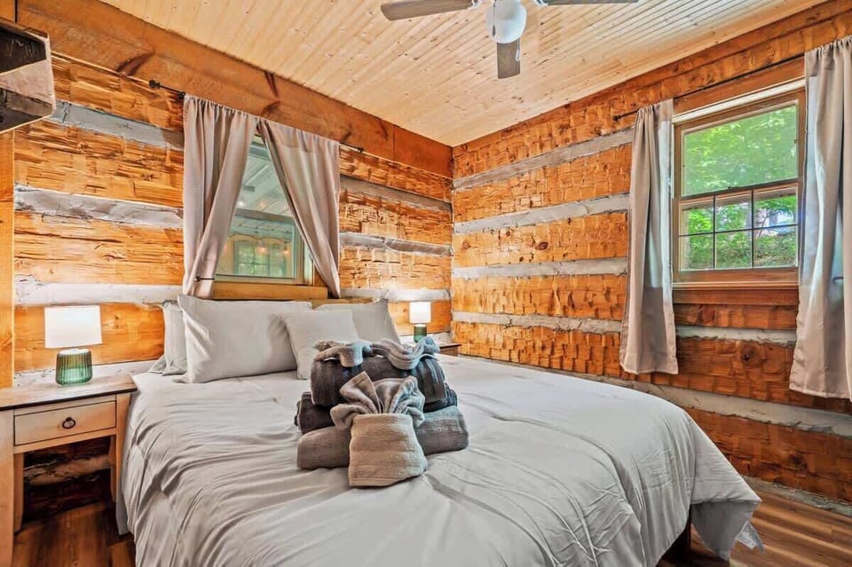 Cozy meets cabin charm in this inviting bedroom featuring a plush king bed, fresh linens, and rustic log walls.