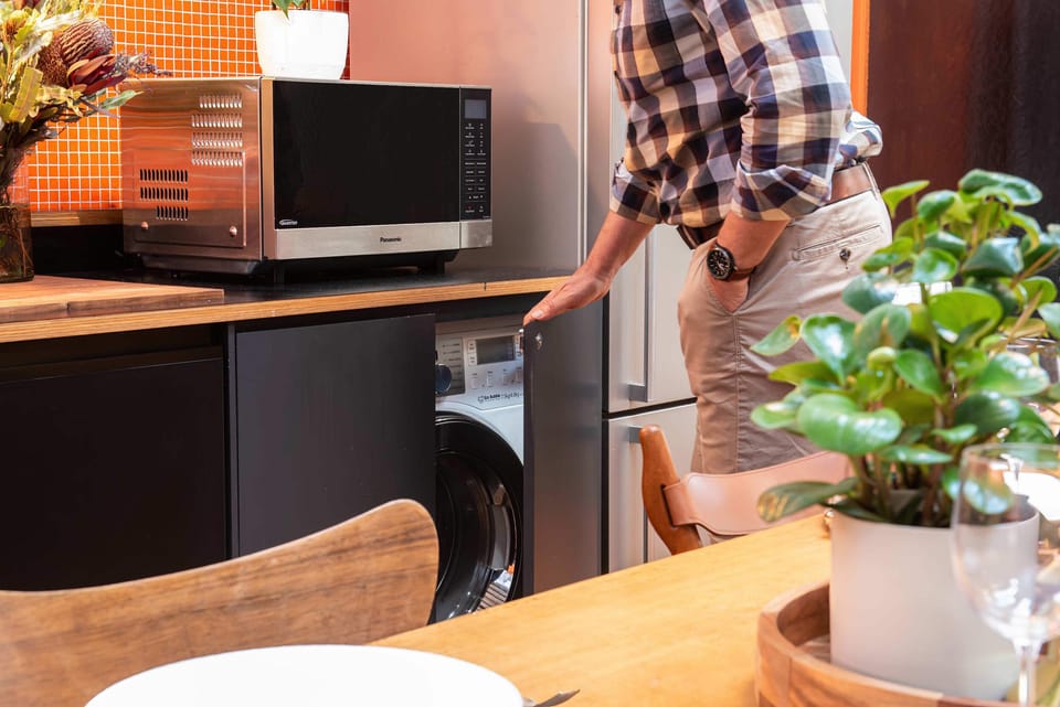 Washing machine behind cupboards in kitchen under microwave