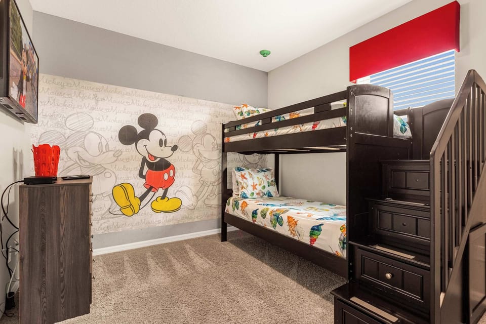 Delight your kids with this charming Mickey Mouse-themed room, complete with cozy bunk beds and vibrant decor.