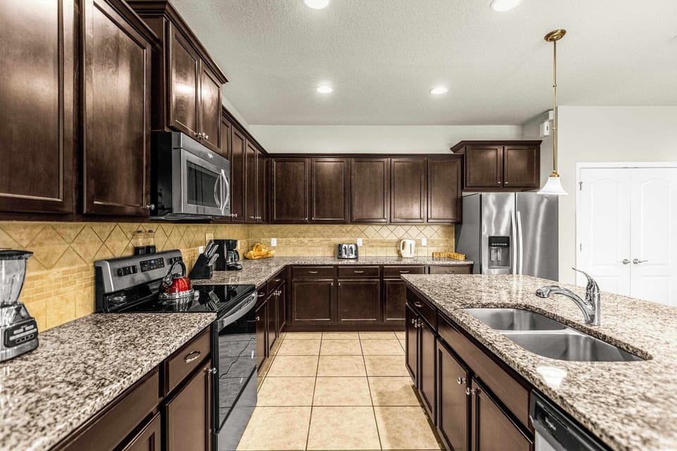 Private kitchen with expansive granite counters, dark wood cabinetry, stainless-steel appliances, and multiple prep areas for group meals.