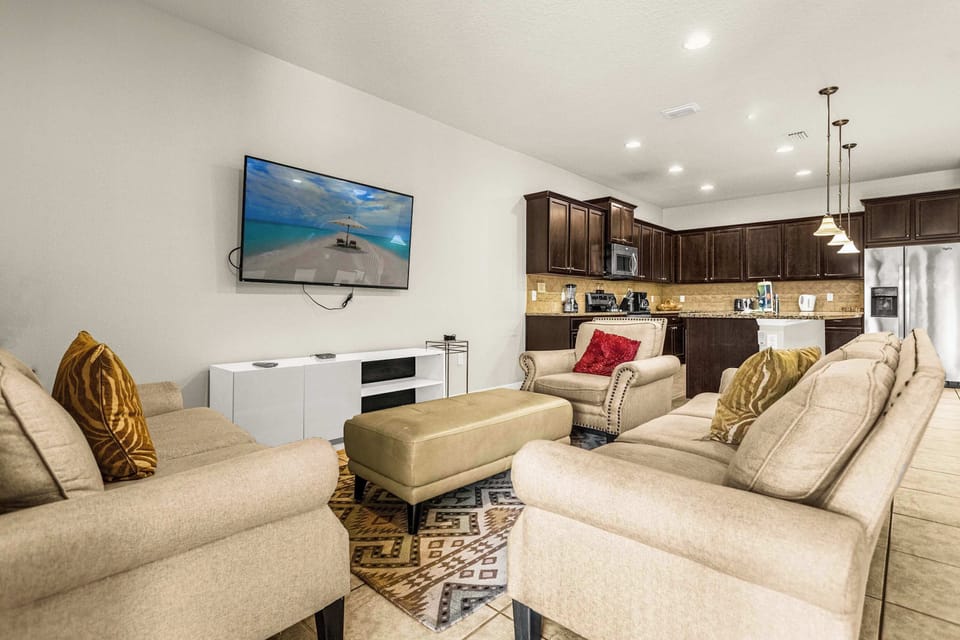 Spacious living room with generous seating, a large beach-view TV, and an open kitchen with a breakfast island for relaxed group gatherings.