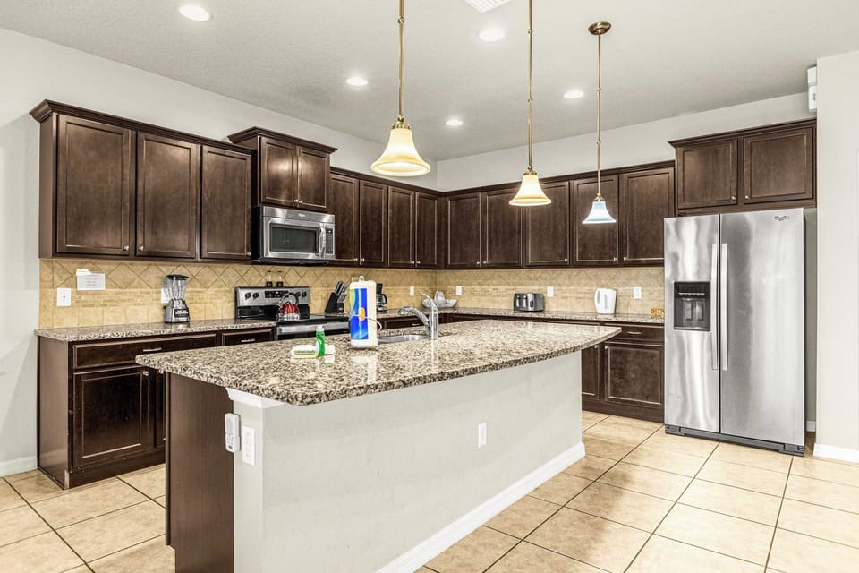 Private kitchen with an expansive granite island, dark wood cabinetry, stainless-steel appliances, and generous prep space for group meals.