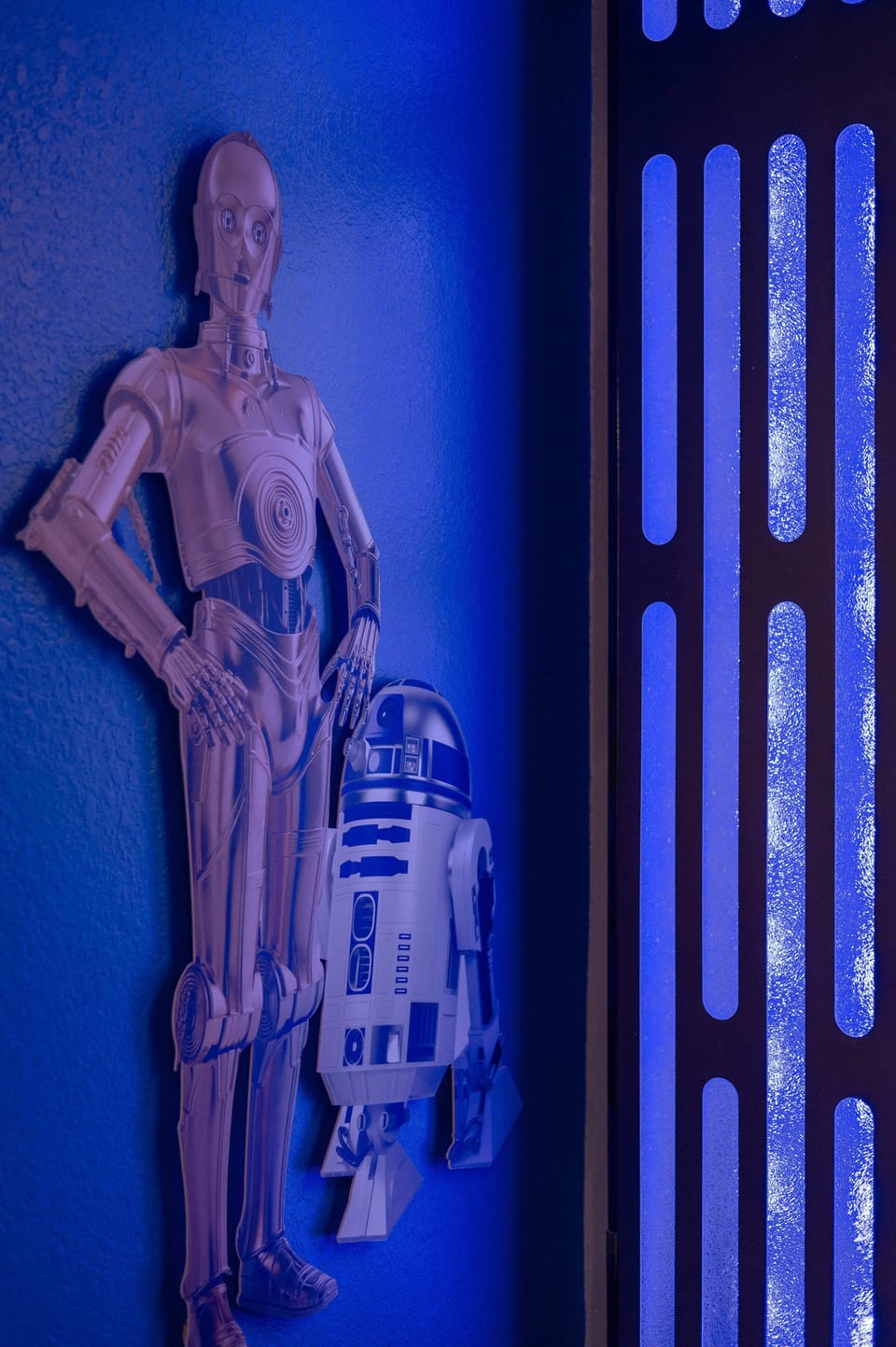 Star wars-themed wall decor featuring c-3po and r2-d2 figures illuminated by blue lighting.