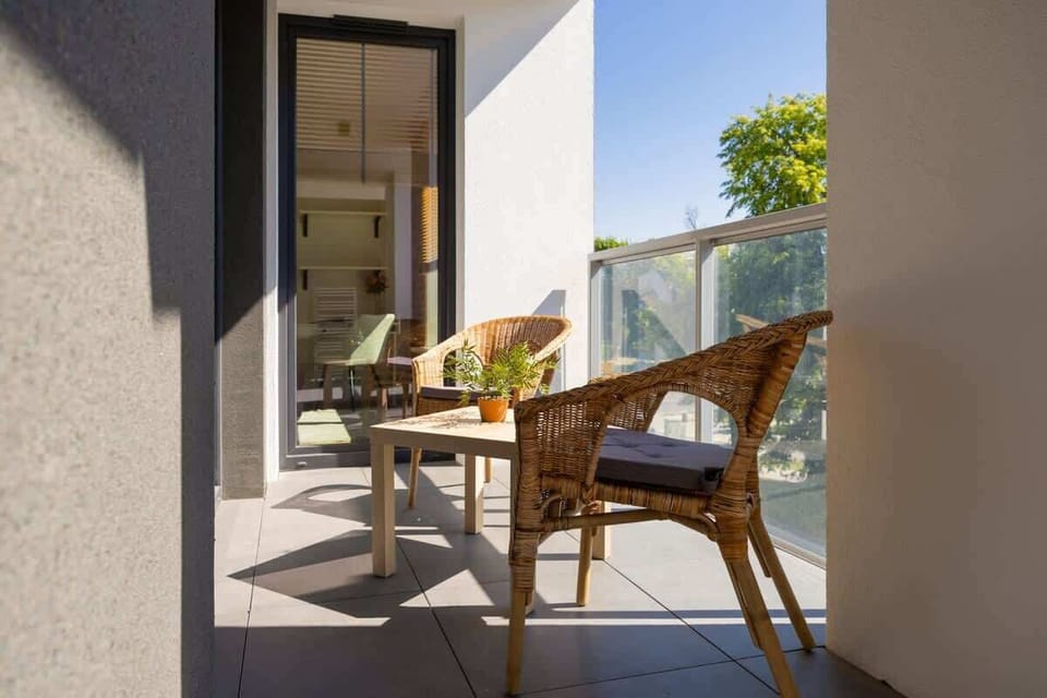 An inviting balcony space with a small wooden table and chairs, offering a private outdoor retreat with a view of the surrounding greenery.