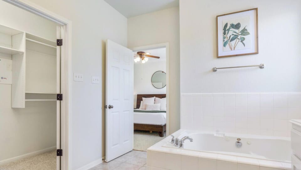 Primary suite bathroom with soaking tub, shower, double sink, and walk in closet