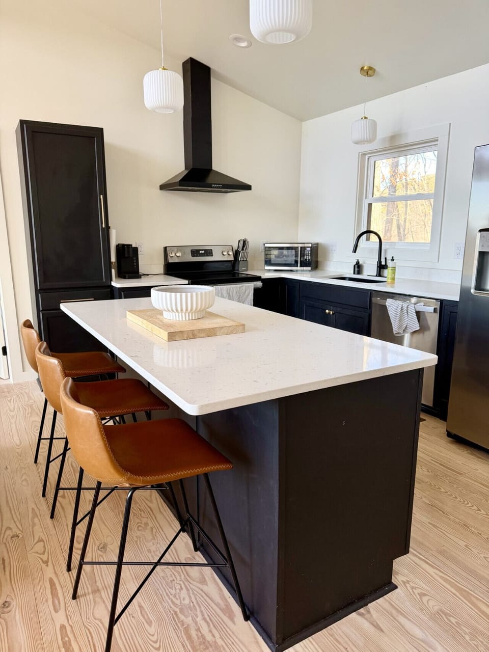 This modern kitchen in our Lake cabin is bright and fully equipped for your stay.  Featuring dark cabinetry, stainless steel appliances, quartz countertops, and a spacious island with seating, it`s perfect for morning coffee or gathering after a day on th