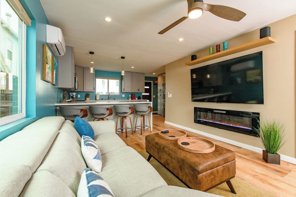 Super comfortable, open space living room features an 8 foot sliding glass door directly to the front deck creating extended room. It's climate controlled with a 75" TV, a fireplace, spacious sofa, and a real leather recliner chair. 