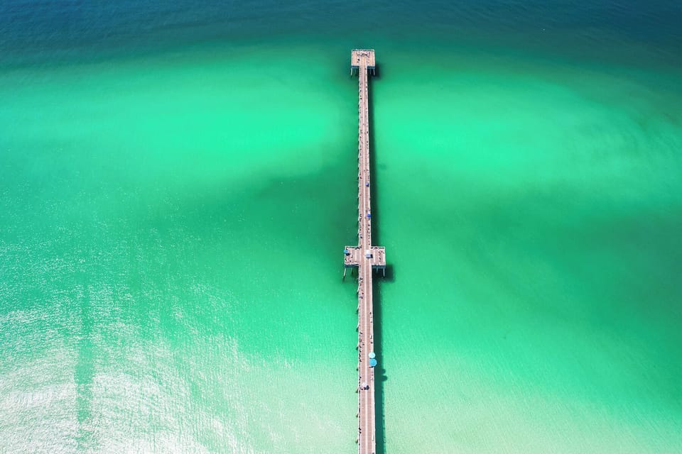 A stunning wooden pier extends into crystal-clear turquoise waters, perfect for waterfront access and scenic walks.