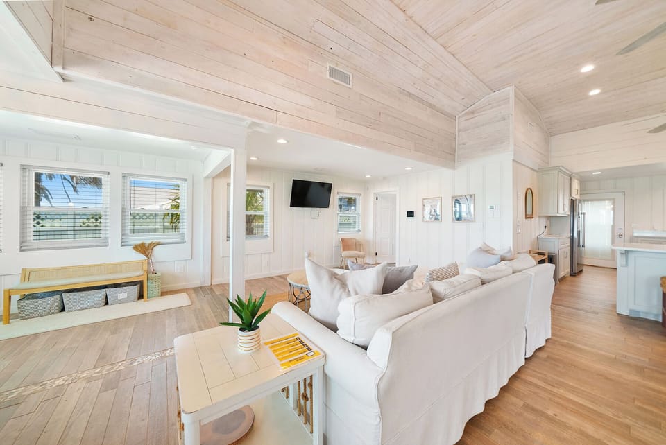 Sink into plush sofas beneath soaring wood-beam ceilings in your bright, coastal-inspired living space with ocean glimpses.