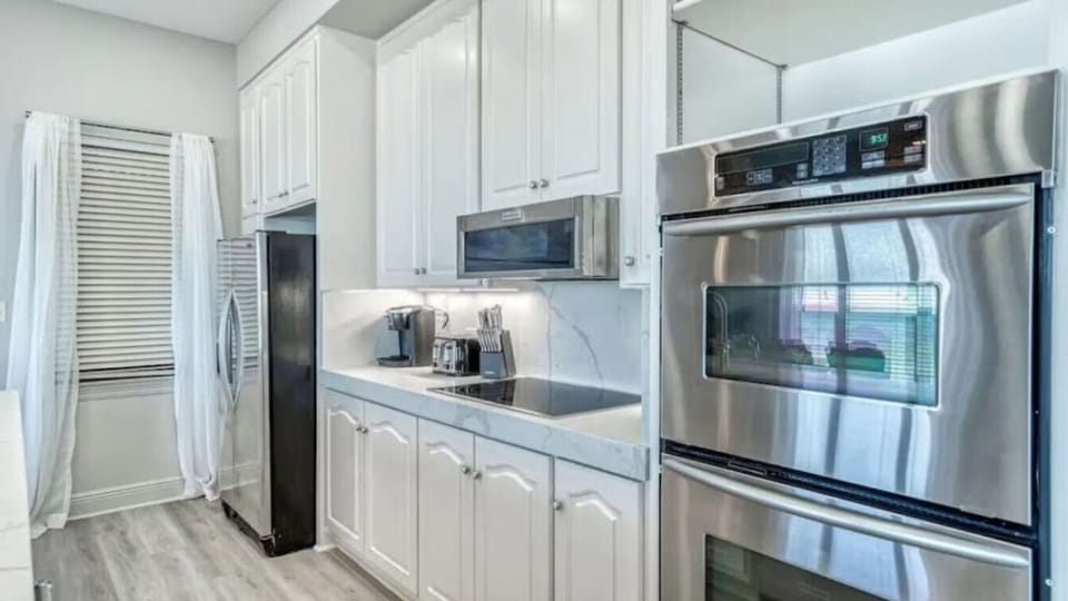 Discover your fully equipped gourmet kitchen with gleaming stainless steel appliances, marble countertops, and crisp white cabinetry perfect for preparing memorable meals.