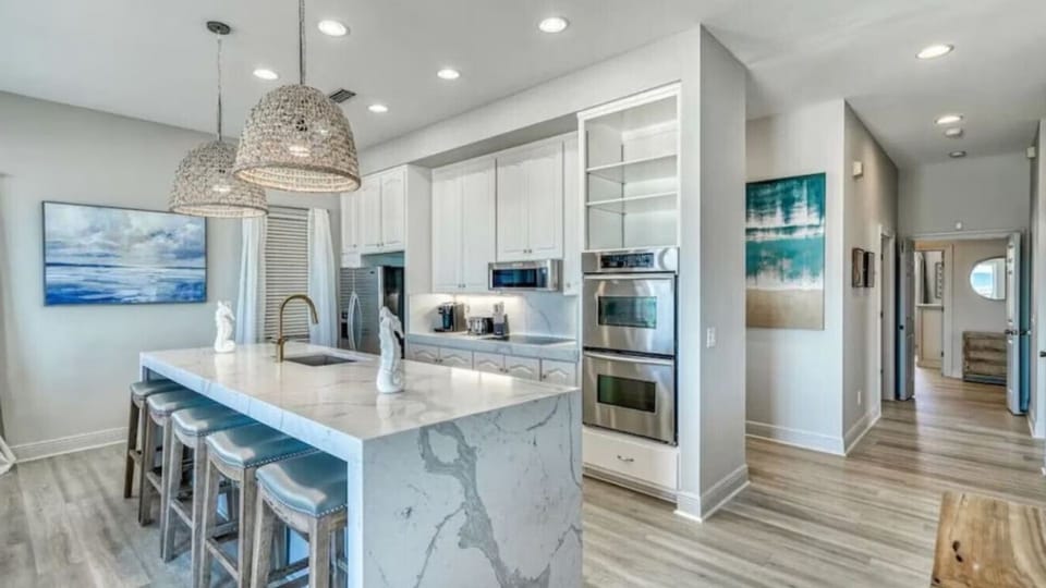 Your chef-inspired kitchen awaits with marble island, stainless appliances, and coastal artwork creating the perfect space for memorable meals.