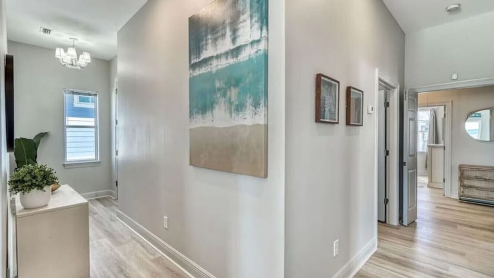 Step into your bright, modern hallway where coastal artwork and warm wood floors create a welcoming first impression.