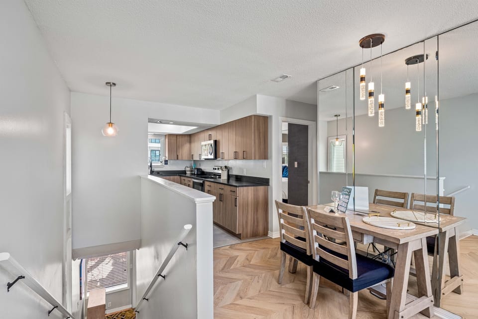 Cook and dine together in your open kitchen and dining space, featuring modern pendant lighting and warm wood accents.