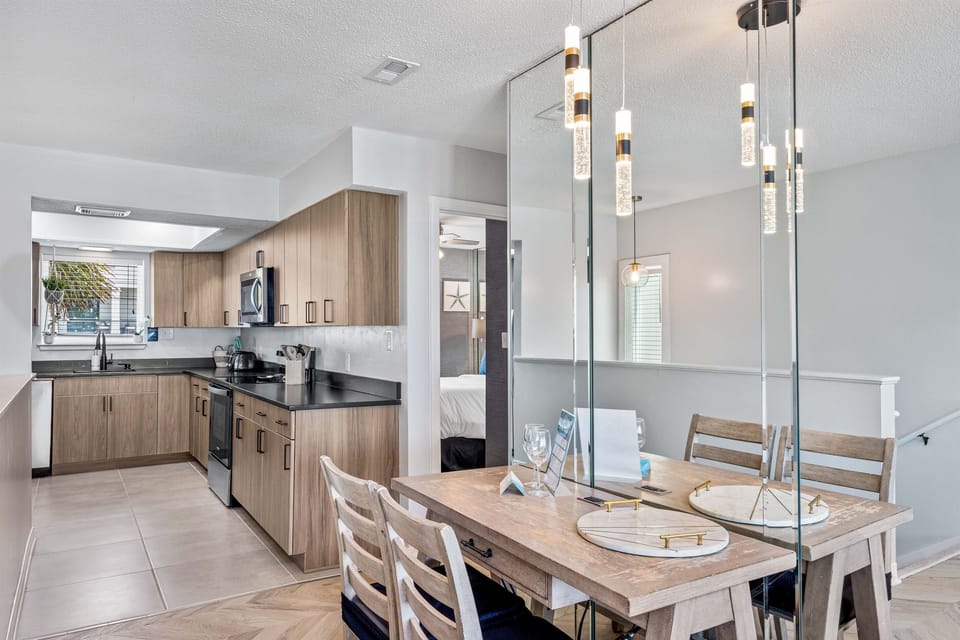 Gather around your sleek dining table beneath modern pendant lights, with a fully equipped kitchen perfect for preparing meals together.