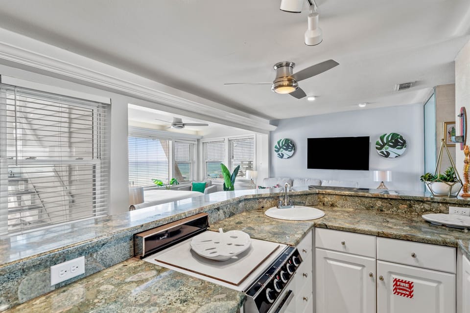 Your modern kitchen flows seamlessly into the living space, featuring granite countertops, stainless appliances, and tropical touches that make cooking feel like vacation.