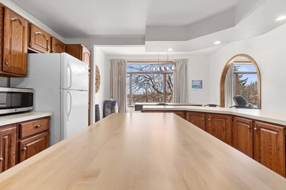 Wraparound counter and dining table beneath the marina-view arched window — built for groups of six.