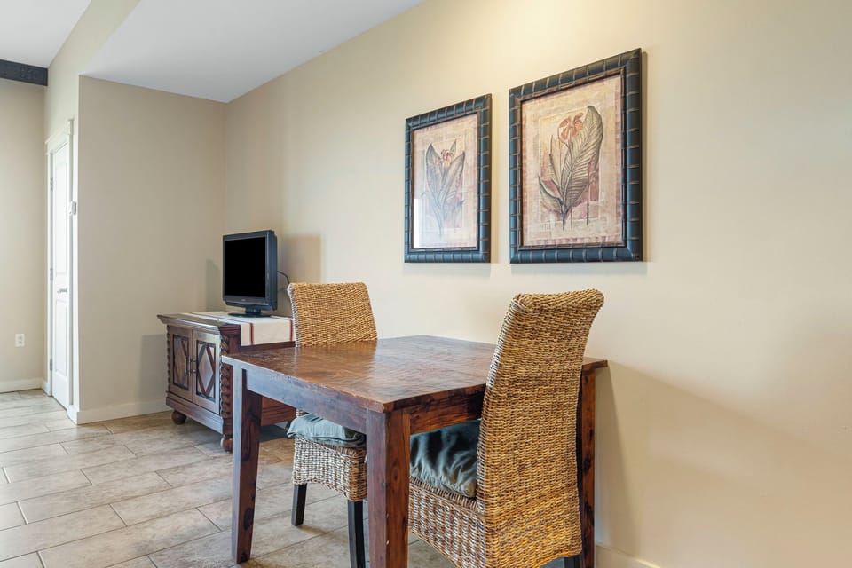 Cozy dining area with rustic wooden table and woven chairs.
