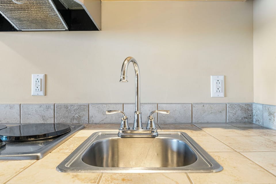 modern kitchen sink with tiled countertop and backsplash