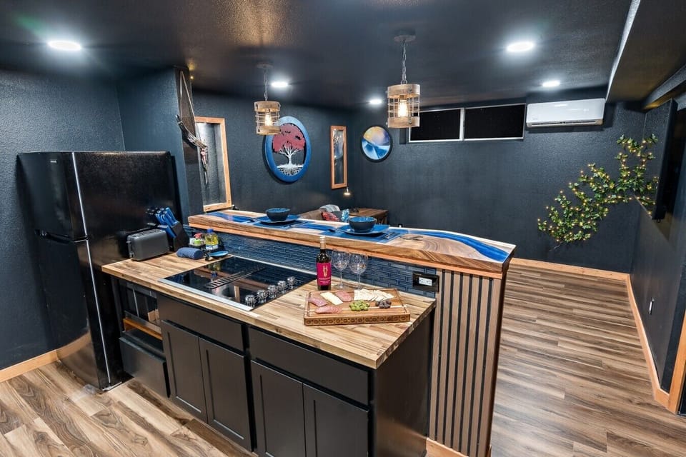 In the Indigo Keep, you are behind the cooktop crafting a meal worthy of the realm while the custom blue epoxy river bar top waits to receive it. Slide the plate across, pour the wine, and enjoy a dining world unlike any other.