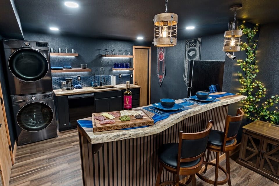Charcuterie laid out, wine uncorked, and two seats at the most dramatic bar top in Reno. Take in the custom live-edge blue epoxy river bar, themed house banners, and warm, lit ivy climbing toward the ceiling above you.