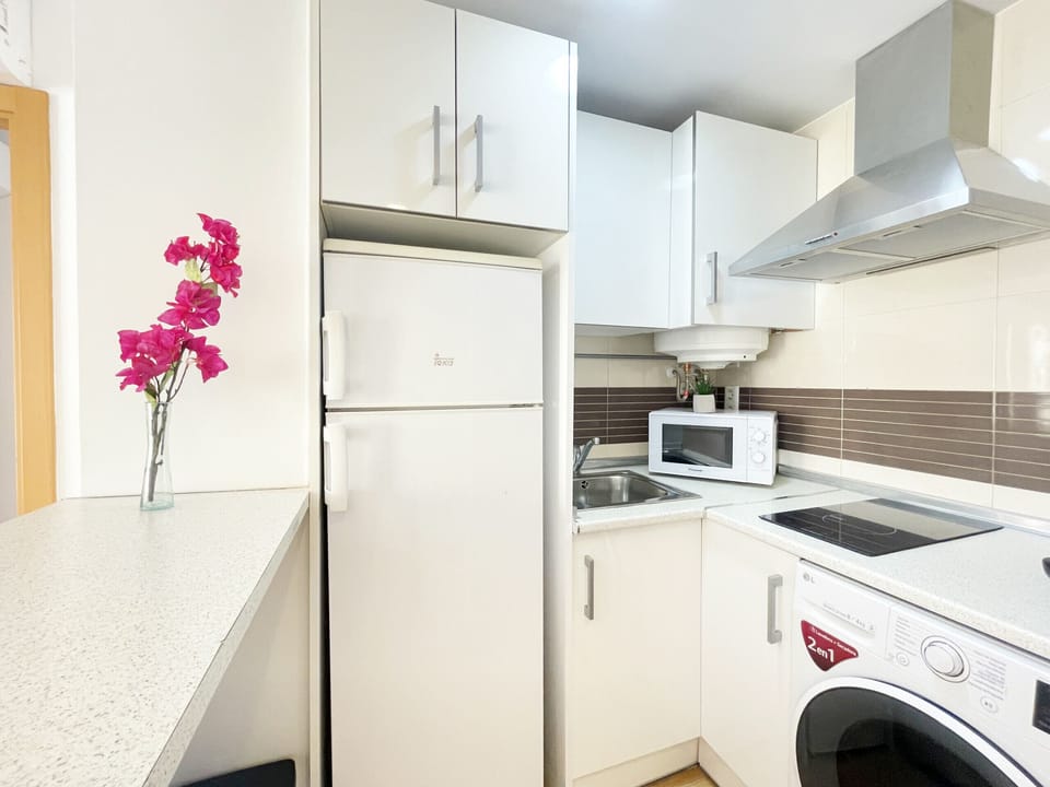 Efficiently configured kitchen in an 'L' shape, maximizing the workspace. Features high-capacity white cabinets and essential integrated appliances for optimal functionality.