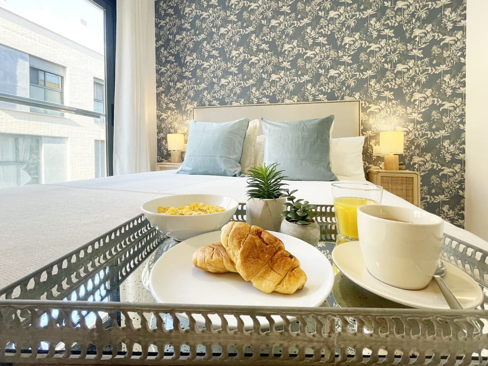 Main bedroom that combines a designer wallpaper with a neutral and bright palette. The upholstered headboard and natural fiber nightstands elevate the aesthetic level of the space.