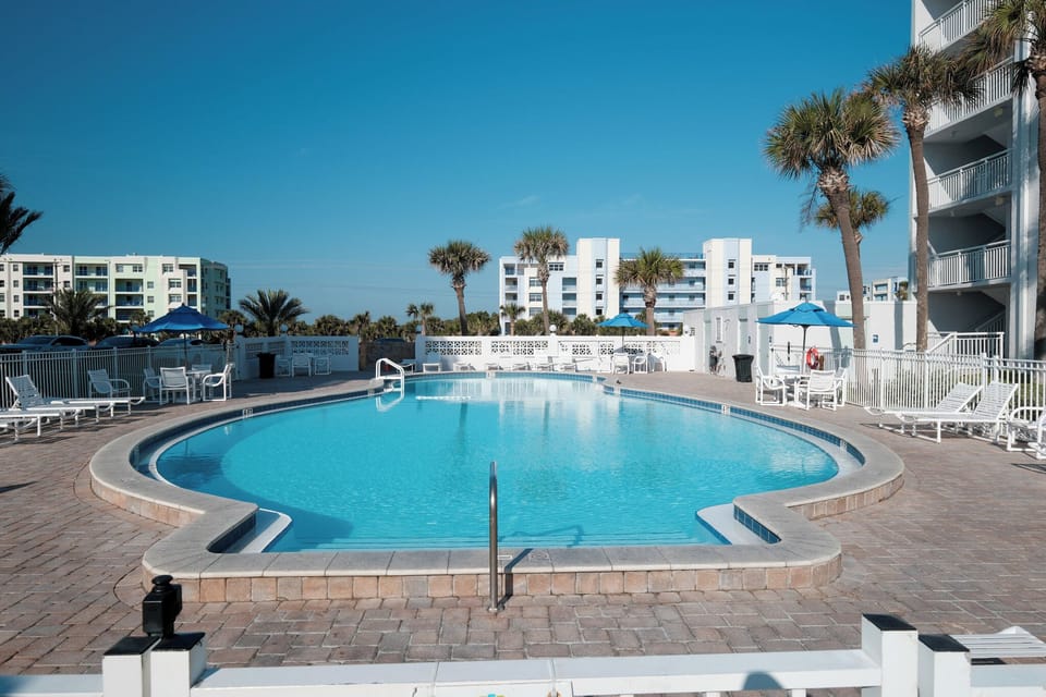 The Shorehom by the Sea pool deck has chairs, tables, and bathrooms