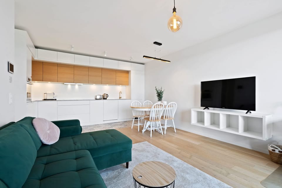 Open living and kitchen area with modern amenities, a comfortable sofa, and a large TV, perfect for relaxation and entertainment.