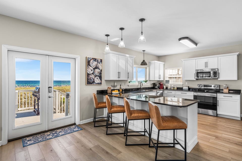 Step into your dream kitchen where ocean views meet culinary comfort. Gather around the island while morning coffee brews and salt air drifts through open doors.