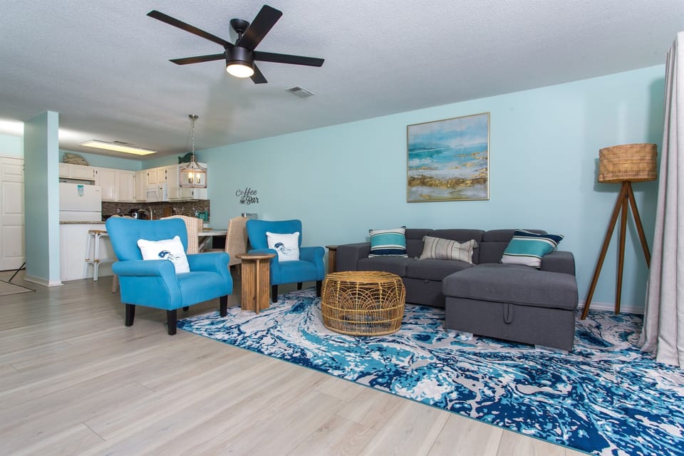 This open space living room and kitchen in a beach house exemplifies the perfect blend of functionality, comfort, and coastal charm