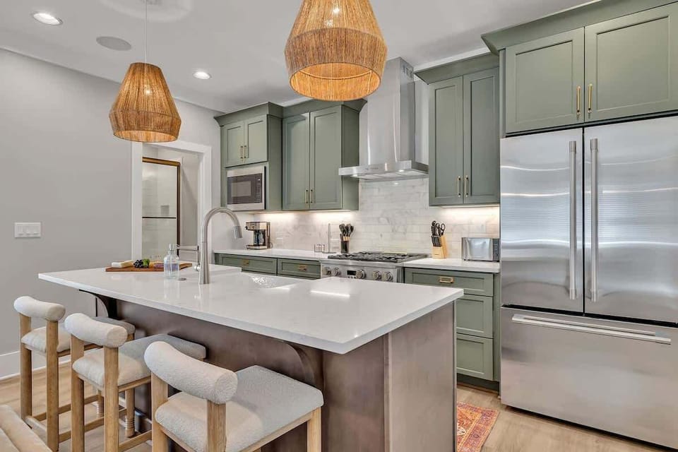 2nd Floor: Fully equipped kitchen stocked with all culinary essentials featuring stainless-steel appliances and a kitchen island offering ample counter space and bar seating.