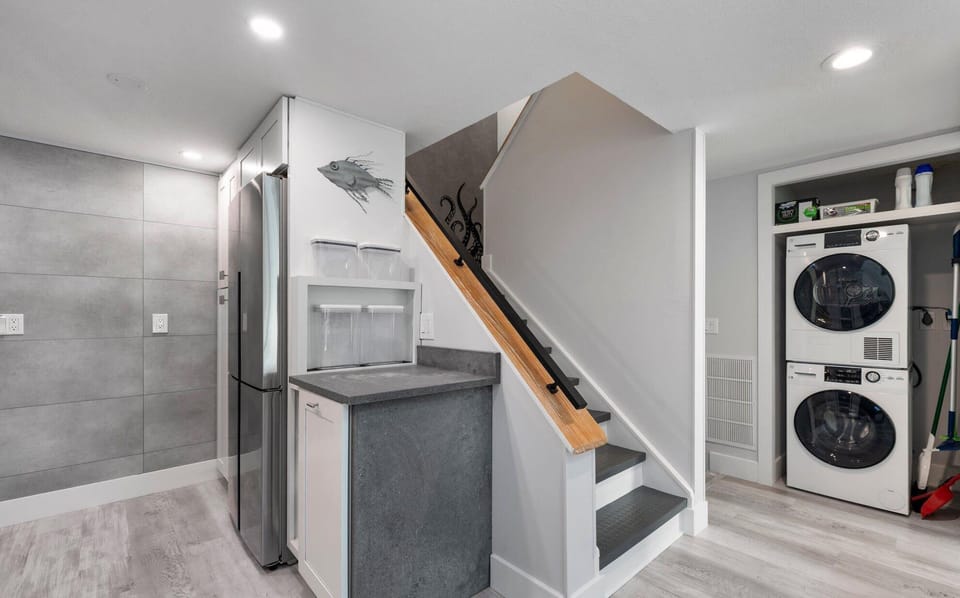 Modern kitchen area with stacked washer and dryer next to a staircase.