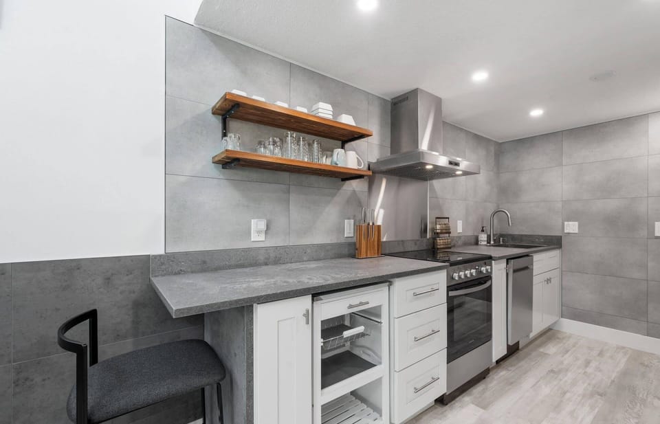 Modern kitchen with concrete countertops and open wooden shelving for glassware.