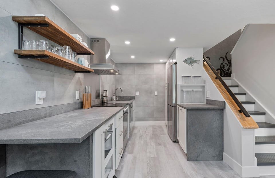 Modern kitchen with concrete countertops and open wooden shelving.