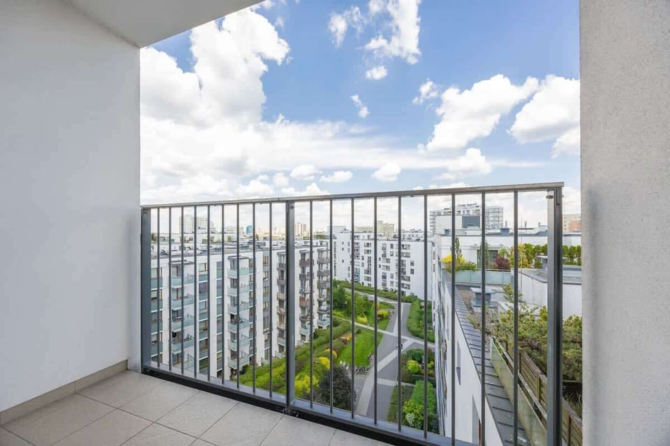 A vibrant aerial view of the apartment complex and nearby buildings. Blue skies and greenery enhance the atmosphere.