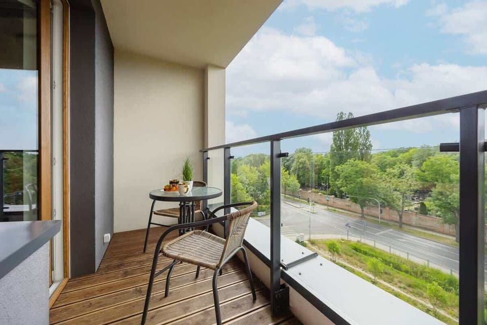 A cozy balcony with a table and chairs overlooking greenery. The outdoor space is perfect for relaxing or enjoying coffee.