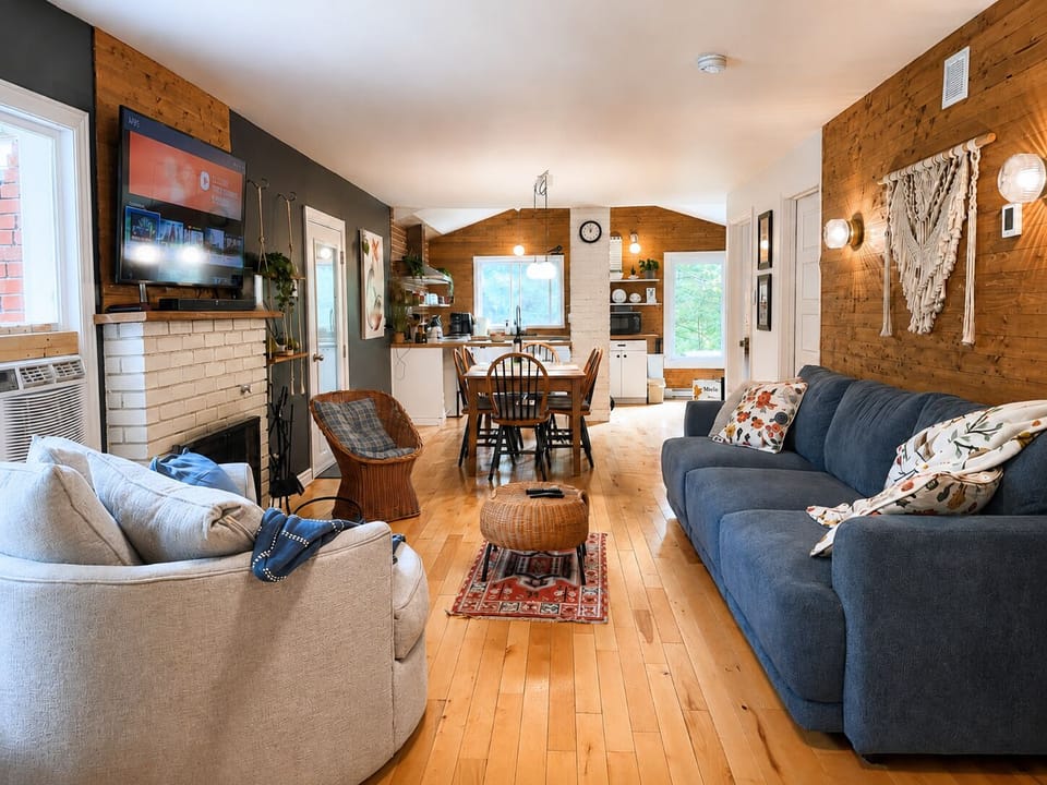 Open living area with cozy fireplace, TV, dining space, bright kitchen, and comfortable seating